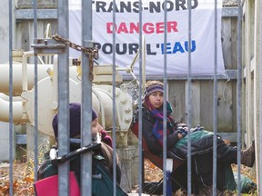 Protesters Jeanne Beauchamp, left, and Jessica Lambert Massicotte chain themselves to the gate and the pipeline of a Trans-nord installation in Oka National Park north of Montreal Nov. 18, 2016.