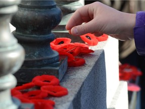 Members of the public leave a poppy at the Cenotaph in Central Memorial Park in downtown Calgary, Alta. on Monday November 11, 2013. as part of the Remembrance Day ceremonies.