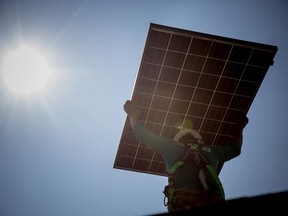 A SolarCity Corp. employee carries a solar panel on the roof during installation at a home in Kendall Park, New Jersey, U.S., on Tuesday, July 28, 2015.