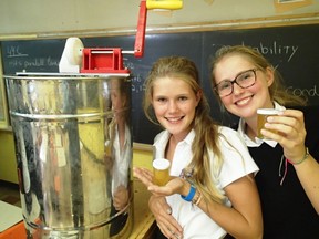 Sisters Julia Ibelings, left, and Merle Ibelings are students at Westmount High School and members of the school's Bee Club. They're pictured during a workshop in September on the extraction and bottling of honey.