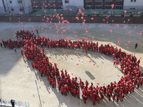 South Korean students make a formation in the shape of the red ribbon, the universal symbol of awareness and support for those living with HIV, as they release balloons during an event to mark the upcoming World AIDS Day on Dec. 1, in Seoul, South Korea, Tuesday, Nov. 29, 2016.