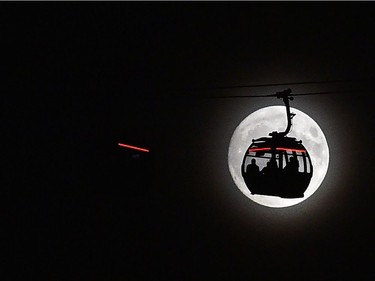 The moon rises behind a car on the Emirates Air Line (cable car) in London's Docklands Nov. 13, 2016. Tomorrow, the moon will orbit closer to the earth than at any time since 1948.