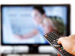 Out of focus TV LCD set and remote control in man's hand isolated over a white background.