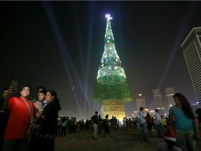 A Sri Lankan family takes photographs standing near an enormous artificial Christmas tree as others gather around it in Colombo, Sri Lanka, Saturday, Dec. 24, 2016. Sri Lanka has unveiled a towering Christmas tree, claiming to have surpassed the world record for the tallest artificial Christmas tree.