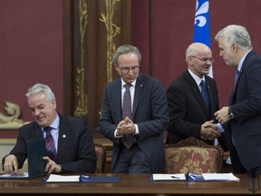 Quebec Premier Philippe Couillard, right, and Richard Lehoux, president of the Quebec Federation of Municipalities (FQM) shake hands at the signature of an agreement to recognize municipalities as proximity governments Tuesday, December 6, 2016 at the legislature in Quebec City. Bernard Sevigny, president of the Quebec Municipality Union (UMQ) from the left, and Quebec Municipal Affairs Minister Martin Coiteux, look on.