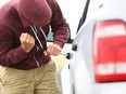 A person attempts to steal a car in broad daylight.