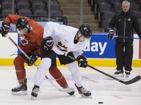 Canada's Mathieu Joseph, left, battles for the puck with Jake Bean as head coach Dominique Ducharme, right, looks on during a practice session ahead of the IIHF World Junior Championship, in Toronto on Saturday, Dec. 24, 2016.