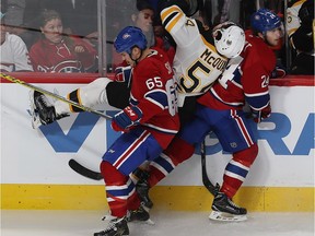 Boston Bruins' Adam McQuaid (54) goes into the plate glass on a hit by Canadiens' Andrew Shaw (65) and Phillip Danault (24) during third period NHL action in Montreal on Monday Dec. 12, 2016.