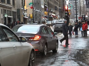 Pedestrians cross the street at the intersection of Peel and Ste-Catherine street west on December 14, 2016.Local mayors have come out demanding Montrealers be allowed to turn right on red lights.