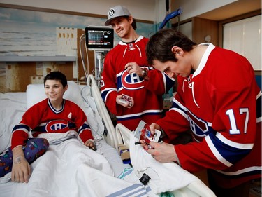 Elowan Gingras smiles as Montreal Canadiens defenceman Jeff Petry and centre Torrey Mitchell, right, sign shirts and cards for him during the Montreal Canadiens annual visit to the Shriner's Hospital for Children in Montreal on Wednesday Dec. 14, 2016.
