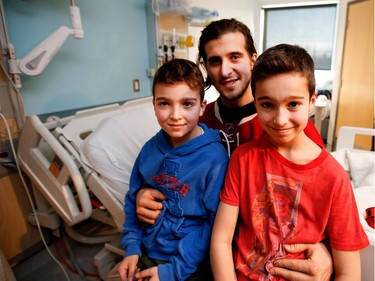 Zachary Dubrovsky, left, 8 years old, and his brother Joshua, 11, sit on Montreal Canadiens left wing Phillip Danault for a picture during the Montreal Canadiens annual visit to the Montreal Children's Hospital in Montreal on Wednesday Dec. 14, 2016.