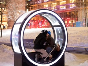 Thomas Goudreault and Helene Maille kiss after they powered the lights in a Loop installation in the Quartier des spectacles Dec. 18, 2016.