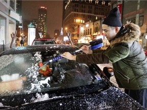 Jason Nie scrapes ice off his windshield on Peel St. after it was coated with freezing rain in Montreal Monday Dec. 26, 2016.