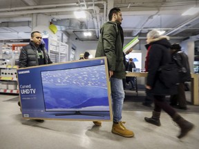 Montrealers Jaswinder Singh, left, and Saranjeet Ghotra carry at big-screen TV through Best Buy on Ste-Catherine St. on Boxing Day in Montreal Monday December 26, 2016.