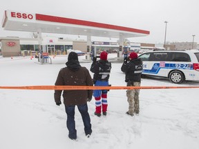 Montreal police officers survey the scene of a fatal shooting outside an Esso gas station and Tim Hortons café at Sherbrooke and St Jean Baptiste in Pointe-aux-Trembles, Dec. 5, 2016.