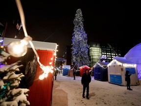 Pedestrians walk past a large, but thin, Christmas tree in Quartier des spectacles in Montreal on Monday December 5, 2016.