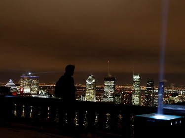 A man looks out to the skyline from the lookout on Mount Royal in Montreal on Tuesday December 6, 2016. Fourteen lights light the sky to mark the victims of the Polytechnique massacre.