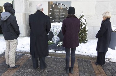Joel Girard-Lauziere, left, Christophe Guy, Clara Levy-Provencal and Michele Thibodeau-DeGuire, right, share a moment of silence at the plaque commemorating the 14 women killed at École Polytechnique Dec. 6, 2016, the 27th anniversary of the massacre.