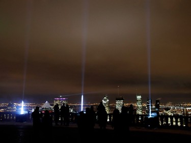 People look out to the skyline from the lookout on Mount Royal in Montreal on Tuesday December 6, 2016. Fourteen lights light the sky to mark the victims of the Polytechnique massacre.