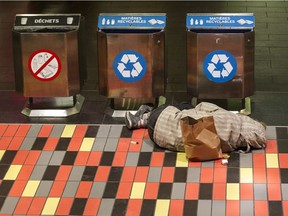 An unidentified man sleeps beside garbage cans inside the Guy Concordia métro station in downtown Montreal,  Dec. 7, 2016. A dozen Montreal groups are working to find permanent housing for 2,000 chronically homeless people by 2020.