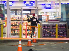 A Montreal police officer enters a dépanneur at an Esso gas station where a woman was shot overnight.