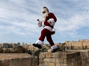 A Palestinian man wears a Santa Claus costume as he walks atop Jerusalem's Old City walls, on December 23, 2016, as Christians around the world prepare to celebrate the holy day.