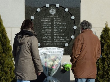 People look at the memorial plaque in honour of the women at École Polytechnique on the 27th anniversary of massacre in Montreal, Dec. 6, 2016.