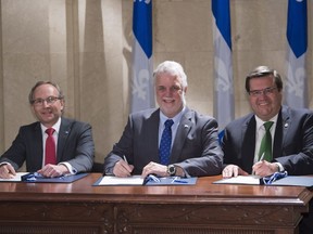 Quebec Premier Philippe Couillard, flanked by Quebec Public Security Minister and Municipal Affairs Minister Martin Coiteux, left, and Montreal Mayor Denis Coderre sign an agreement with the city of Montreal Thursday, December 8, 2016 at the Premier's office in Quebec City. The Quebec government is presenting legislation that would give more governing power to Montreal.