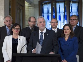 Quebec Premier Philippe Couillard, centre, announces a public inquiry on relations between natives and public services, Wednesday, December 21, 2016 at the premier's office in Quebec City. Couillard is flanked by Quebec Minister for Rehabilitation, Youth Protection and Public Health Lucie Charlebois, left, and Quebec Justice Minister Stephanie Vallee, right, Quebec Chief of First Nations Ghyslain Picard, back row from the left, Quebec Native Affairs Minister Geoffrey Kelley, Quebec Public Security Minister and Municipal Affairs Minister Martin Coiteux and native leader Matthew Coon Come.