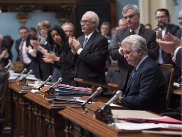 Quebec Premier Philippe Couillard, right, is applauded by members of the legislature after paying respect to the victims of the Polytechnique tragedy that killed 14 women 27 years ago, Tuesday, December 6, 2016 at the legislature in Quebec City.