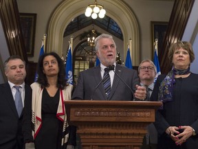 Quebec Premier Philippe Couillard flanked by members of his cabinet, speaks at a news conference marking the end of the fall session at the National Assembly, in Quebec City on Friday, December 9, 2016. From the left, Sébastien Proulx, Dominique Anglade, Philippe Couillard, Gaétan Barrette, Hélène David.