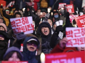 Protesters shout during a rally calling for South Korean President Park Geun-hye to step down in Seoul, South Korea, Friday, Dec. 9, 2016. The letters read "Arrest, Park Geun-hye."