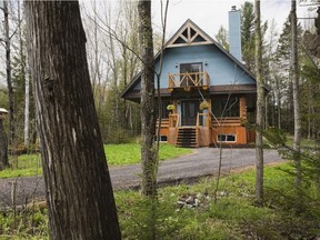 The combination of several types of exterior finishing materials - vertical wooden planks, logs, blue Canexel siding, including aged timber framing and an asphalt shingles roof puts this small home in the hybrid category. (Photo by Perry Mastrovito)