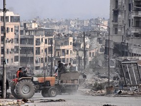 Syrians use a tractor to collect belongings in the former rebel-held Zebdiye district in the northern Syrian city of Aleppo on December 23, 2016 after Syrian government forces retook control of the whole embattled city.