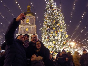Ukrainians pose for a selfie against the background of main Christmas tree decorated for Christmas and New Year celebrations near to St. Sophia's Cathedral on St. Nicholas Day in Kiev, Ukraine, Monday, Dec. 19, 2016.