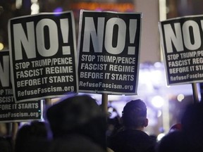 People attending an anti-Trump rally and protest hosted by filmmaker Michael Moore hold signs as they listen to speakers on a stage set up in front of the Trump International Hotel, Thursday, Jan. 19, 2017, in New York. President-elect Donald Trump, a New Yorker, is scheduled to take the oath of office Friday in Washington. (AP Photo/Kathy Willens)