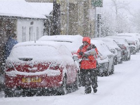 A postman struggles in the snow while making deliveries in Stirling, Scotland, Thursday, Jan. 12, 2017. Snow showers and strong winds are expected across Scotland, Northern Ireland, Wales and the north of England on Thursday. (Andrew Milligan/PA via AP) ORG XMIT: LON804