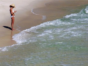A woman checks her cellphone at the beach.