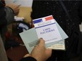 A woman holds her identity card and vote card as she waits to vote for the French left's presidential primaries ahead of the 2017 presidential election, in Marseille, southern France, Sunday, Jan.22, 2017.