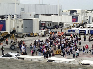 People stand on the tarmac at the Fort Lauderdale-Hollywood International Airport after a shooter opened fire inside a terminal of the airport, killing several people and wounding others before being taken into custody, Friday, Jan. 6, 2017, in Fort Lauderdale, Fla.