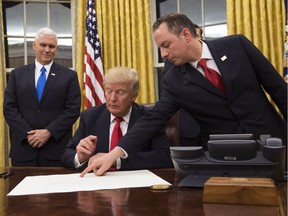President Donald Trump prepares to sign a confirmation for Defense Secretary James Mattis as his Chief of Staff Reince Priebus points to the order while Vice President Mike Pence watches January 20, 2017 in Washington, DC.