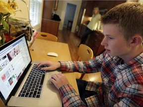 In this Oct. 24, 2013 photo, Mark Risinger, 16, checks his Facebook page on his computer as his mother, Amy Risinger, looks on at their home in Glenview, Ill.