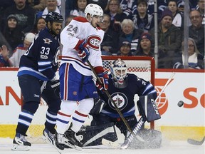 Canadiens' Phillip Danault and Jets' Dustin Byfuglien watch as a point shot heads for Jets goalie Michael Hutchinson during action on January 11, 2017 at the MTS Centre in Winnipeg.