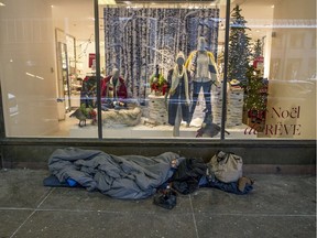 An unidentified man sleeps in a sleeping bag on the sidewalk on Union Ave. beside The Bay department store in downtown Montreal, Dec. 7, 2016.