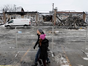 Richard Perey and Catherine Verardo walk past the site of a fire that gutted a neighbourhood mall in the Vimont district of Laval, north of Montreal on Tuesday January 10, 2017.