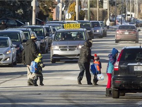 Parents and students cross Shamrock St. during a busy student pick-up period, as they leave the St. Patrick Elementary School in Pincourt, west of Montreal, Friday January 13, 2017.