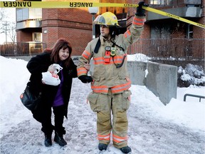 A Montreal fireman helps an evacuated  resident make her way to waiting bus after a woman died in an apartment fire in an old age home in Montreal on Monday January 2, 2017.