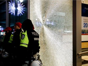 Montreal police stand guard outside police Station 20 after protesters smashed the front window in Montreal on Friday, Jan. 20, 2017.