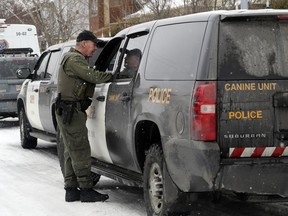 An officer with the Ontario Provincial Police canine unit speaks to a collegue outside a house in Brossard, south of Montreal Friday January 27, 2017, where a woman and her infant child have been missing since April 2014.  The OPP canine unit have dogs that specialize in the location of cadavers and human remains.