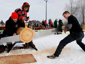 McGill University's Dominic Mercier-Provencher competes in the Single Buck as teammates Olivier Lamar, left, oils his saw and Philip Gauthier films the event during the Intramural-intercollegiate Woodsmen Competition in Montreal on Saturday Jan. 28, 2017.
